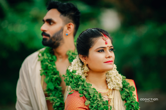 Bride and groom wearing traditional wedding garlands